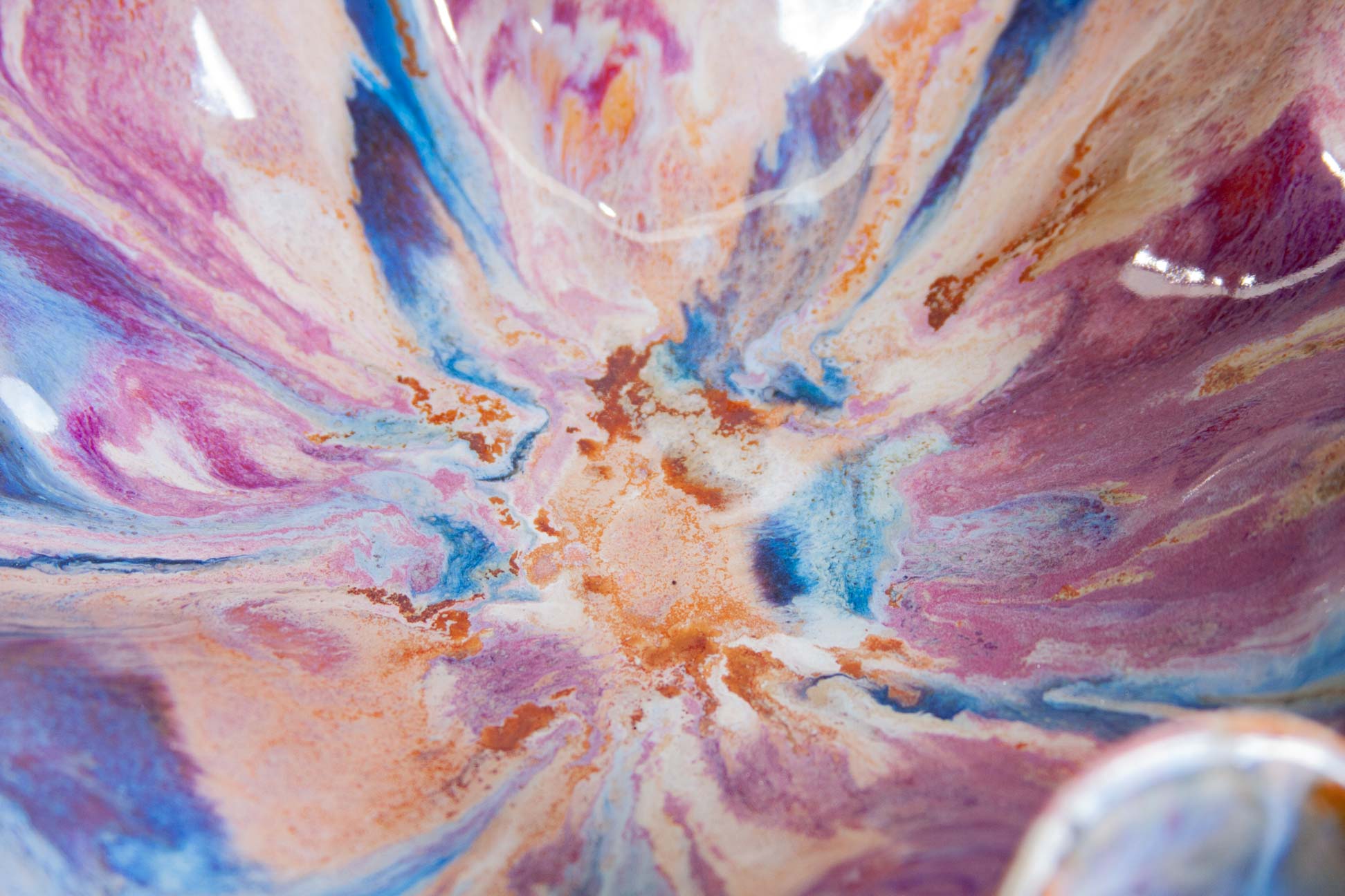 Close-up of a glossy ceramic bowl or dish featuring a marbled abstract pattern with swirls of pink, purple, blue, peach, and white.
