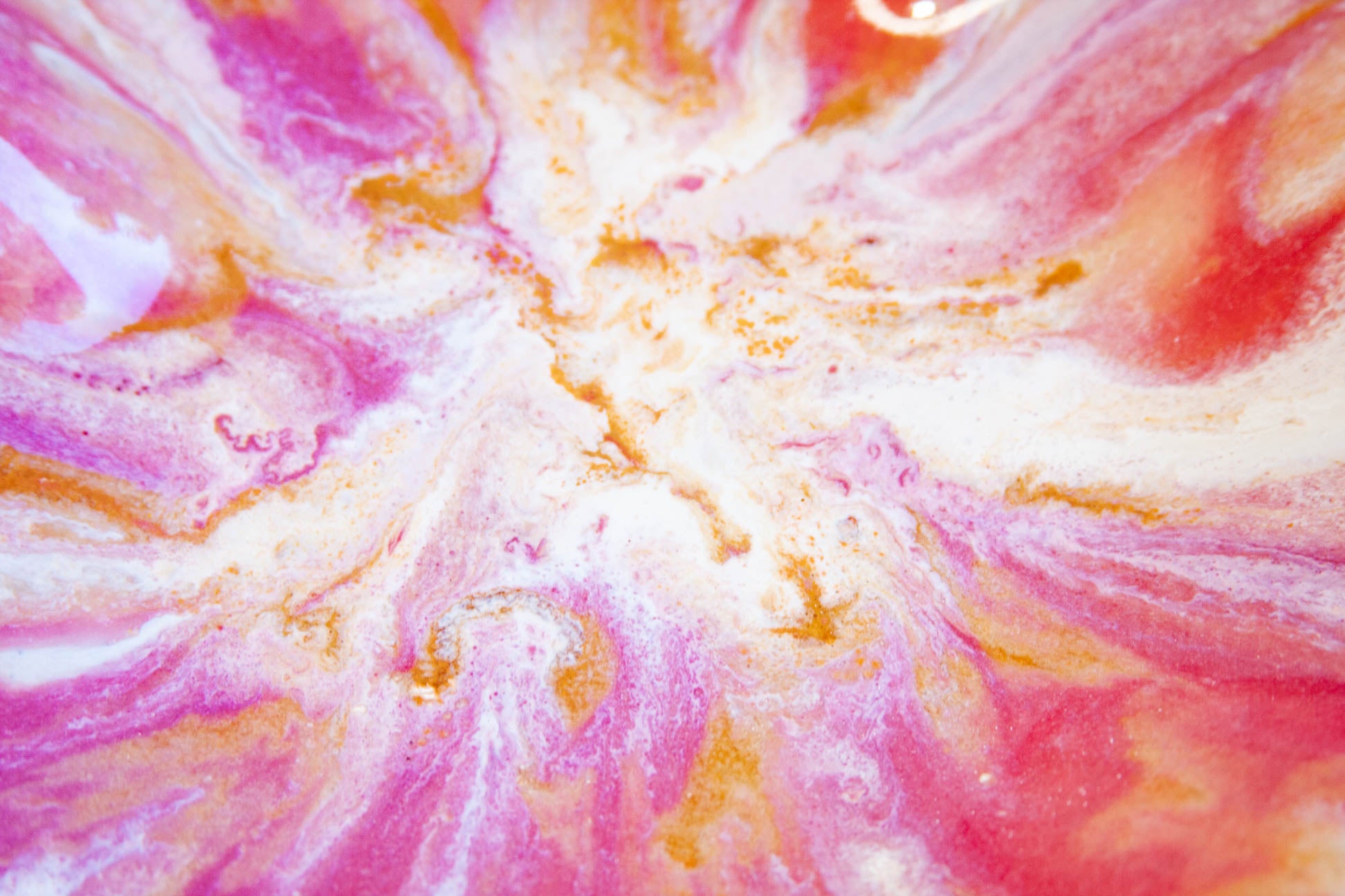 A close-up of a marbled abstract pattern with swirling pink, white, and orange tones, resembling liquid art or a decorative surface.