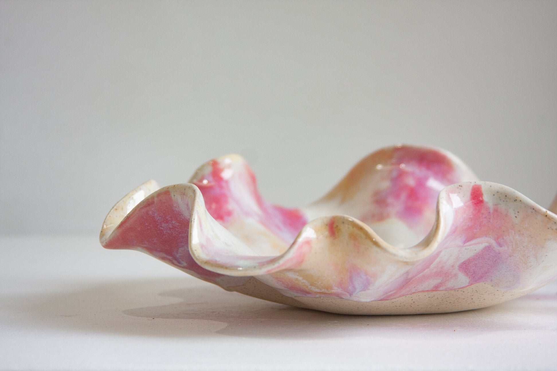 Decorative ceramic dish with pink and beige marbled pattern on a white background