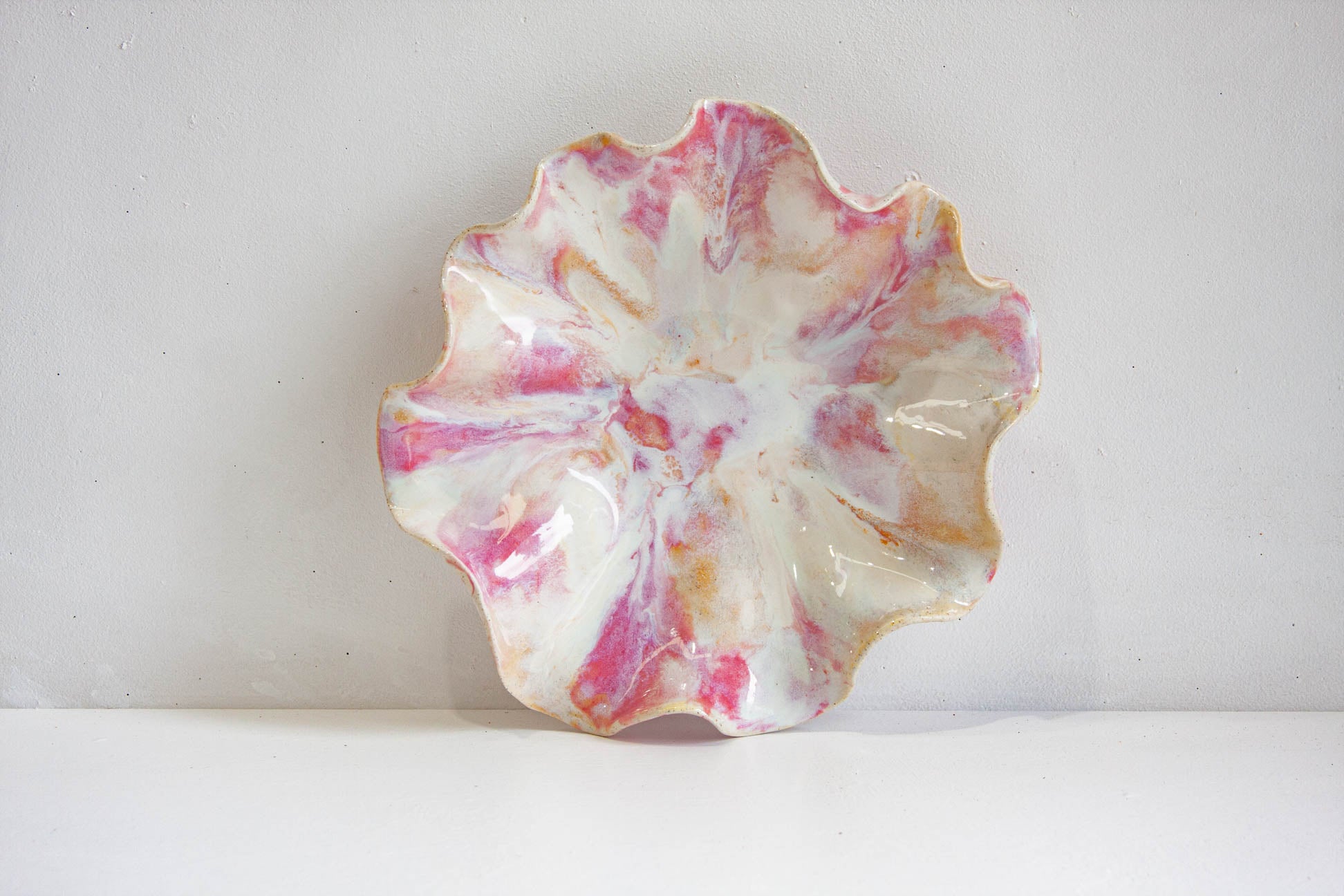 Marbled ceramic plate with pink and orange hues on a white background