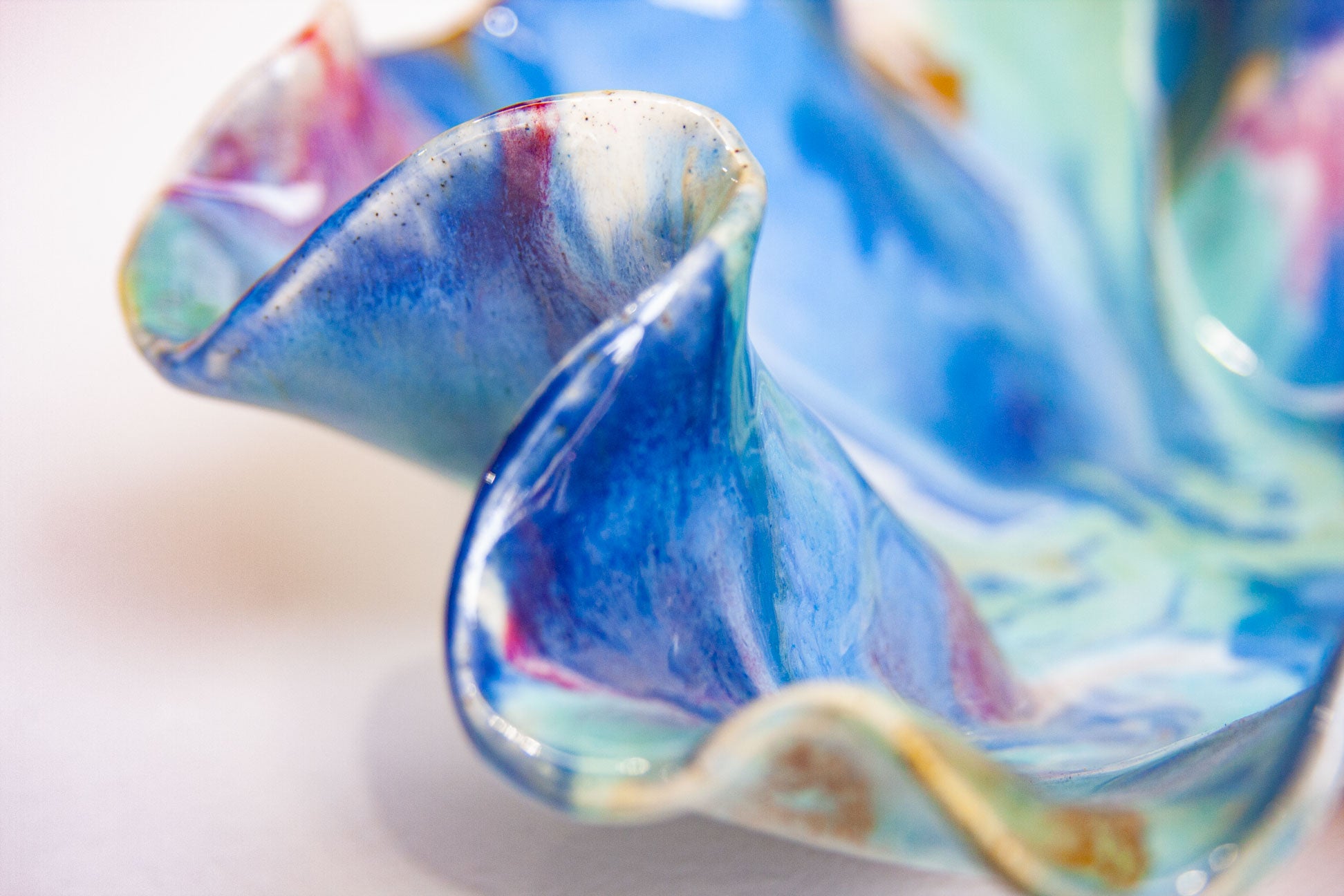 Close-up of a colourful ceramic platter with swirling patterns on a white background