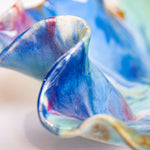 Close-up of a colourful ceramic platter with swirling patterns on a white background