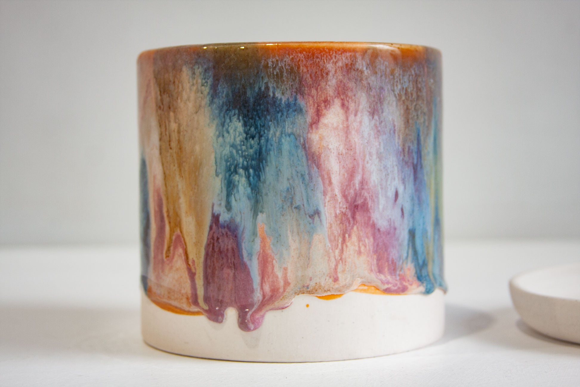close up of pink, peach, brown and blue glazed cylindrical planter