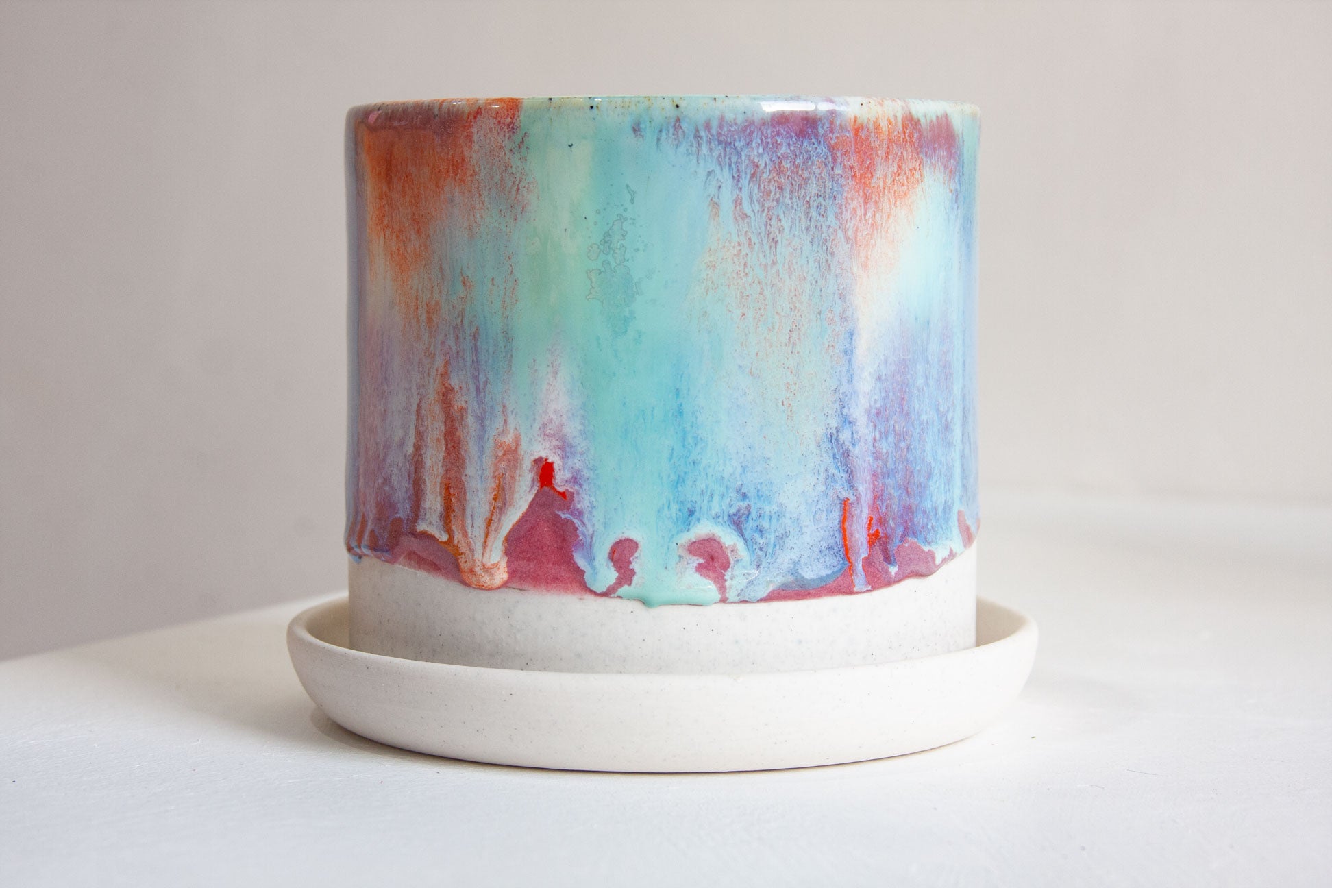 handmade ceramic multicoloured planter on a ceramic saucer.