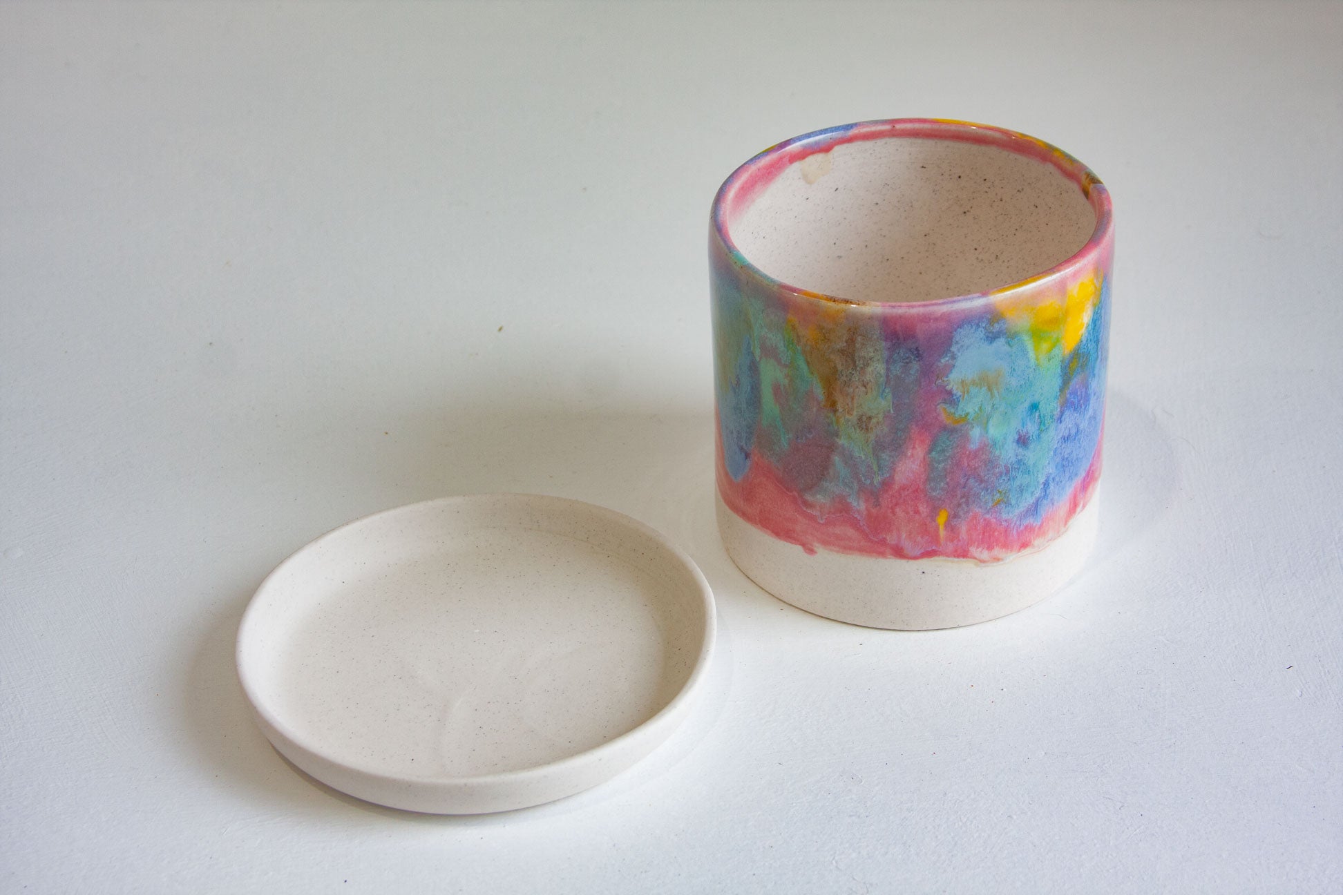 handmade ceramic rainbow planter sitting beside a ceramic saucer dish