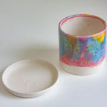 handmade ceramic rainbow planter sitting beside a ceramic saucer dish