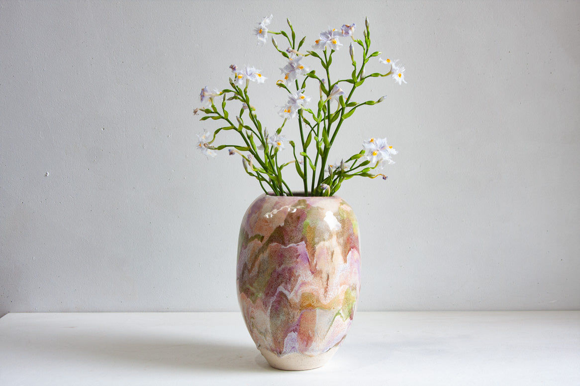 Decorative vase with marbled pattern and small flowers on a plain background
