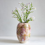 Decorative vase with marbled pattern and small flowers on a plain background