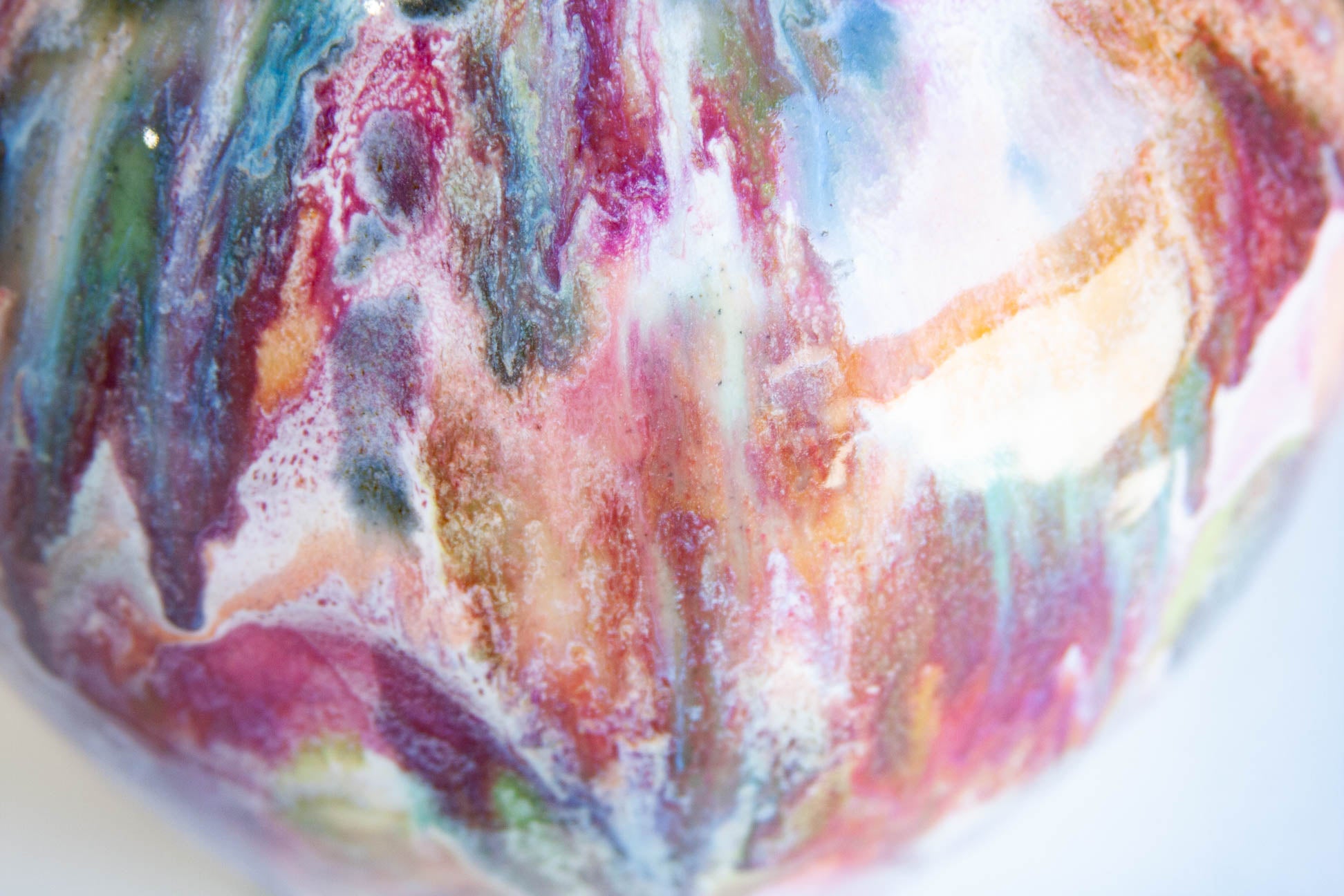 Close-up of a colorful marbled surface with swirling pink, purple, blue, green, orange, and white tones.