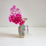 Colorful vase with pink flowers on a white surface and background