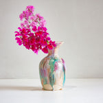 Decorative vase with colorful abstract patterns containing pink flowers on a white background