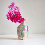 Decorative vase with colorful abstract patterns containing pink flowers on a white background