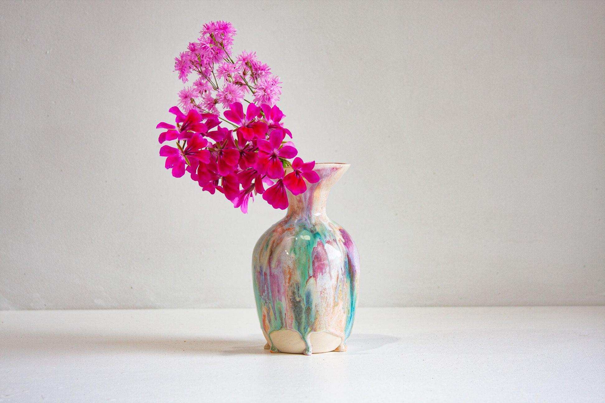 Decorative vase with colorful abstract patterns containing pink flowers on a white background