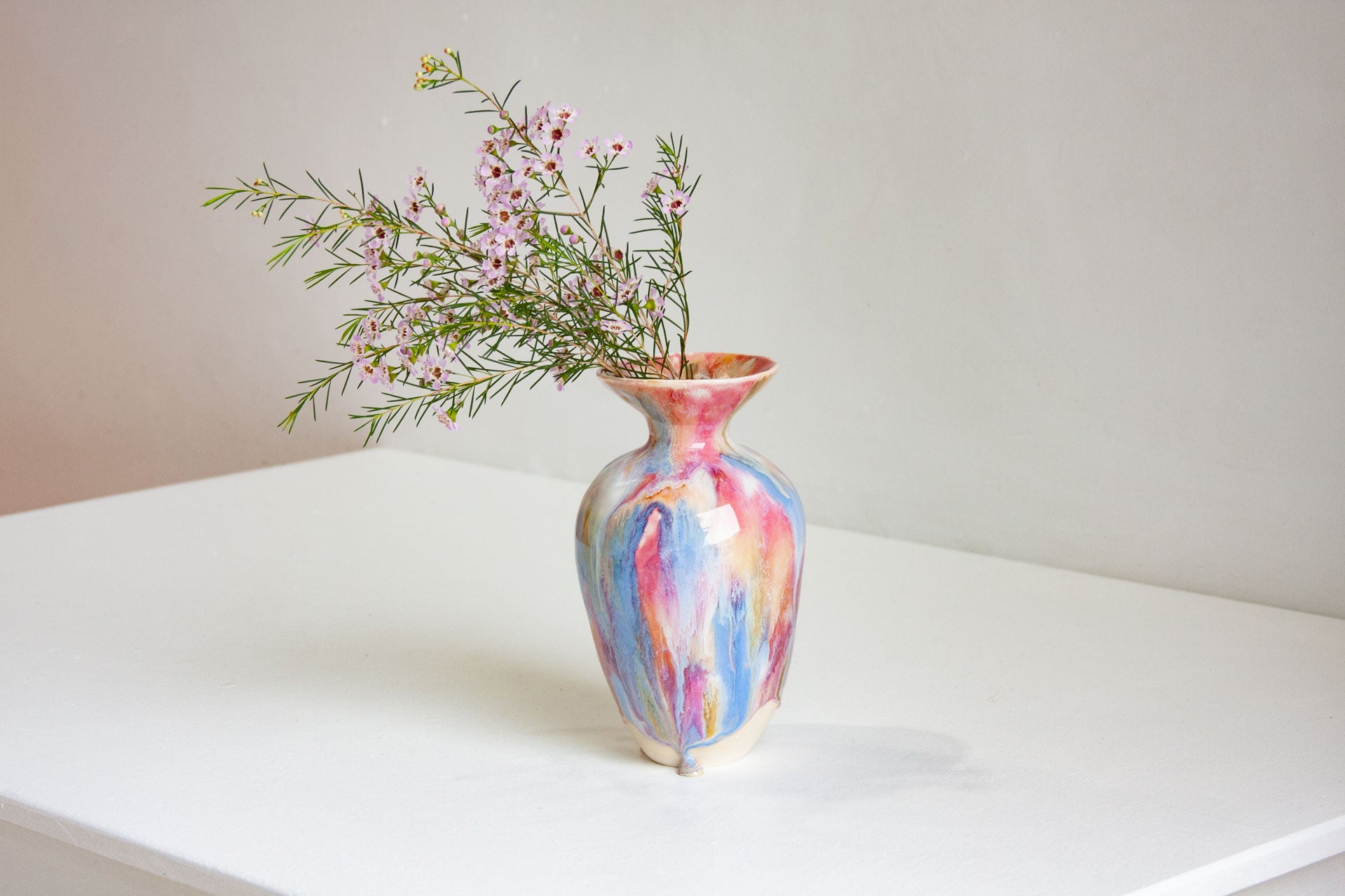 Multicolored vase with flowers on a white surface
