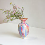 Multicolored vase with flowers on a white surface