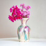 Vase with pink flowers on a white surface and light gray background