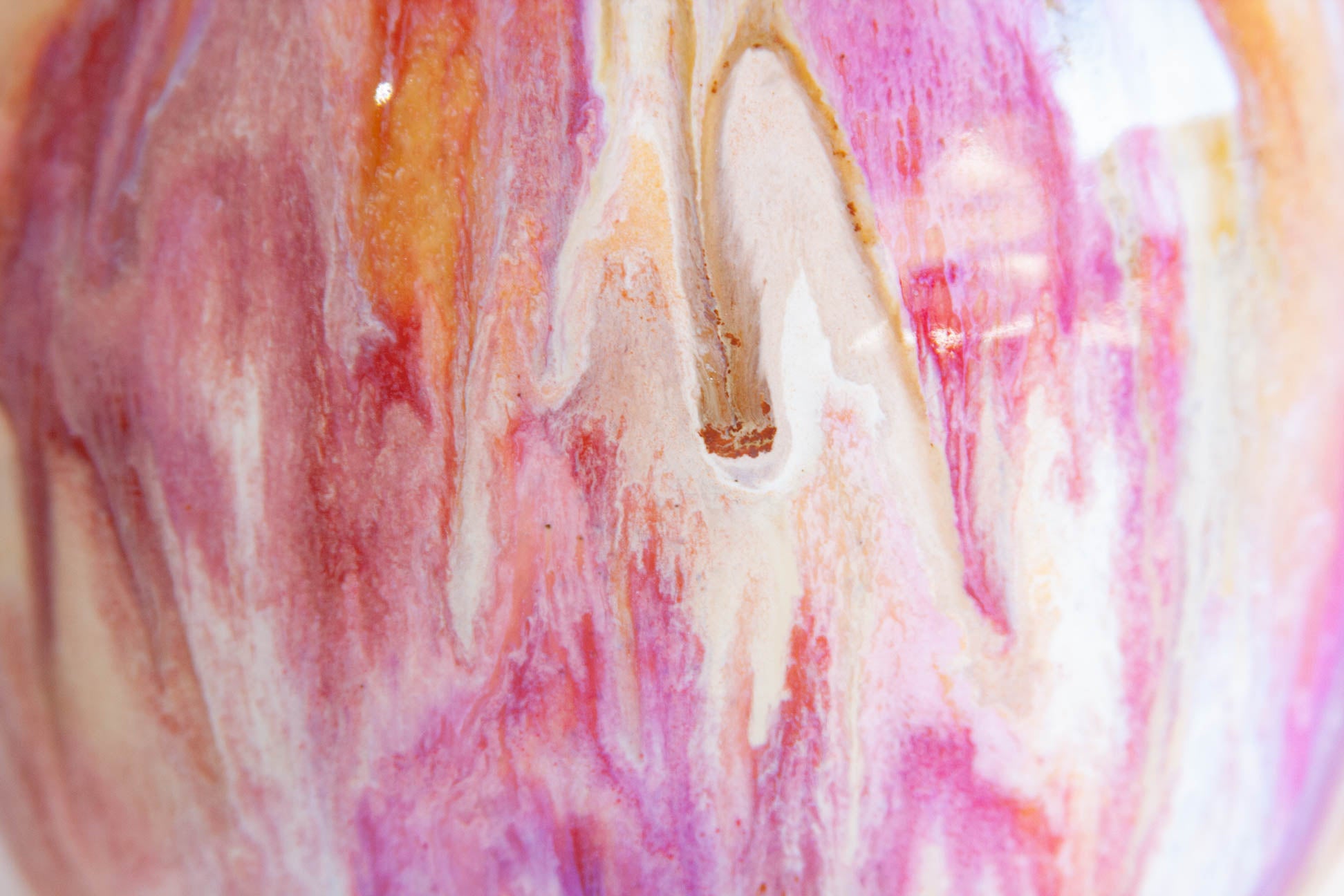 Close-up of a glossy marbled surface with swirling pink, white, peach, and a small gold accent.