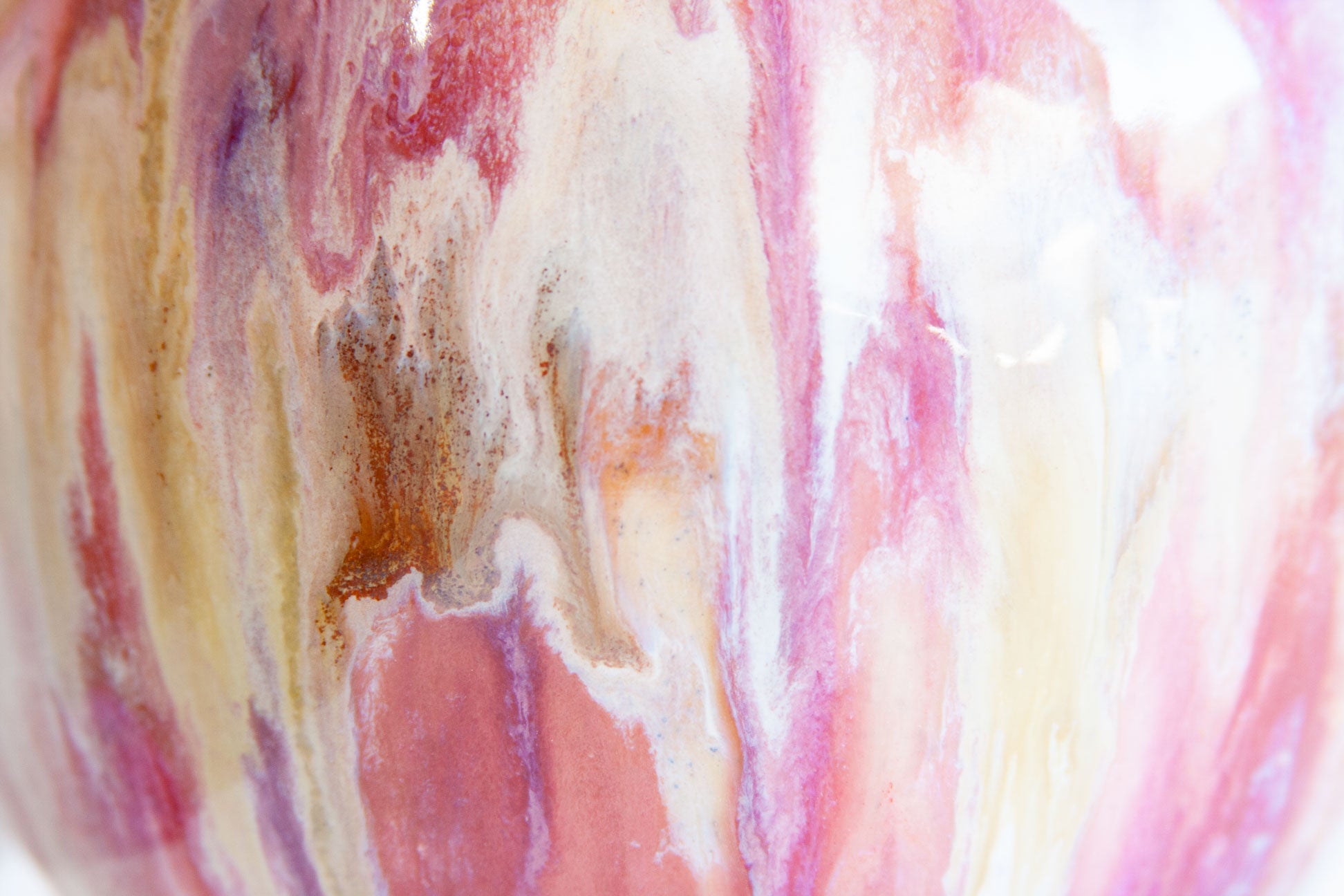 Close-up of a glossy ceramic surface with an abstract marbled pattern in pink, cream, white, and touches of brown and purple.