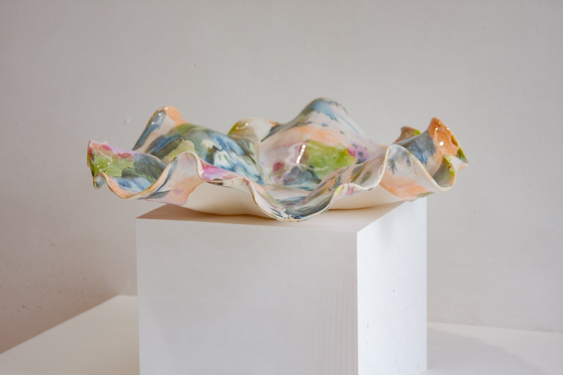 Colourful ceramic bowl on a white pedestal against a plain background