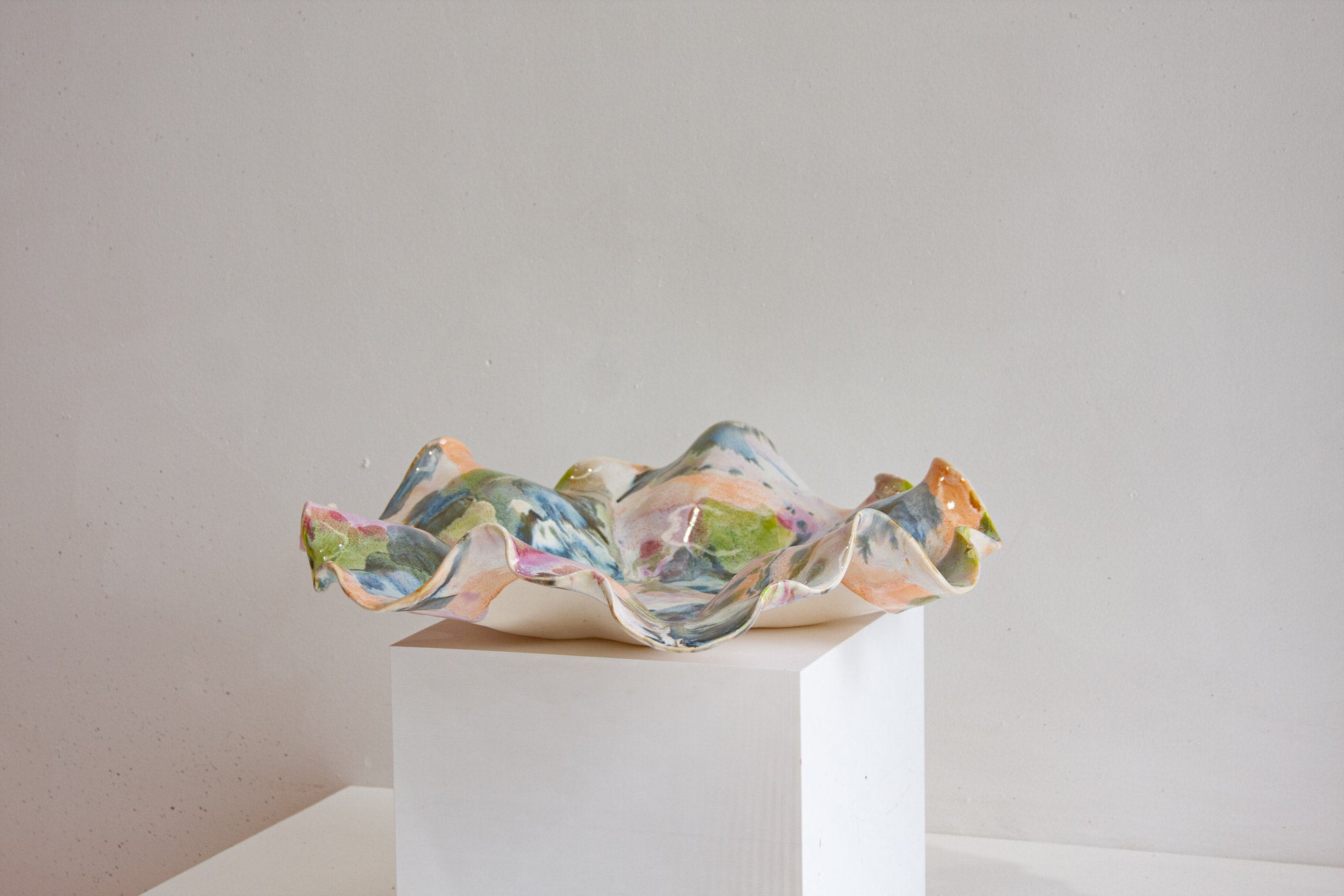 multicoloured sculptural latter on a white pedestal against a plain background