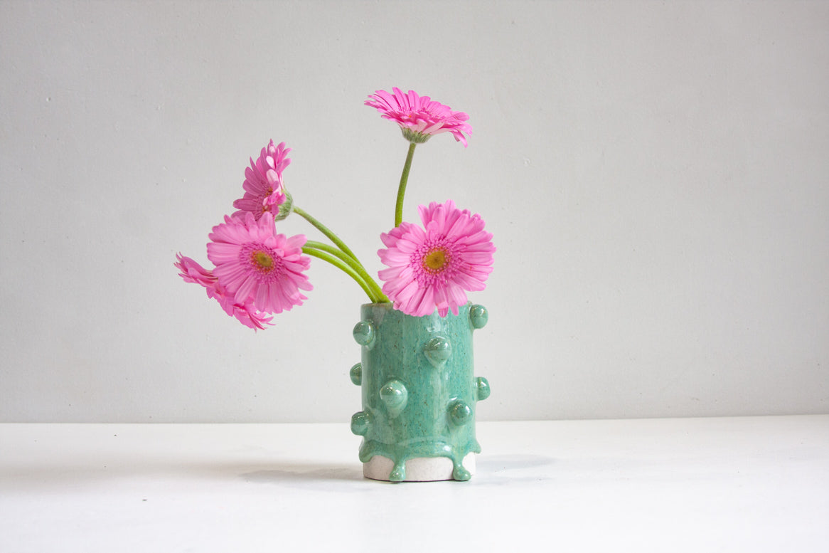 handmade ceramic small cylinder vase with little clay baubles attached to the body of the vase, glazed in green.